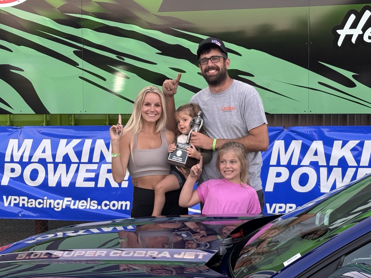 M20 racer and family celebrating beside the race car
