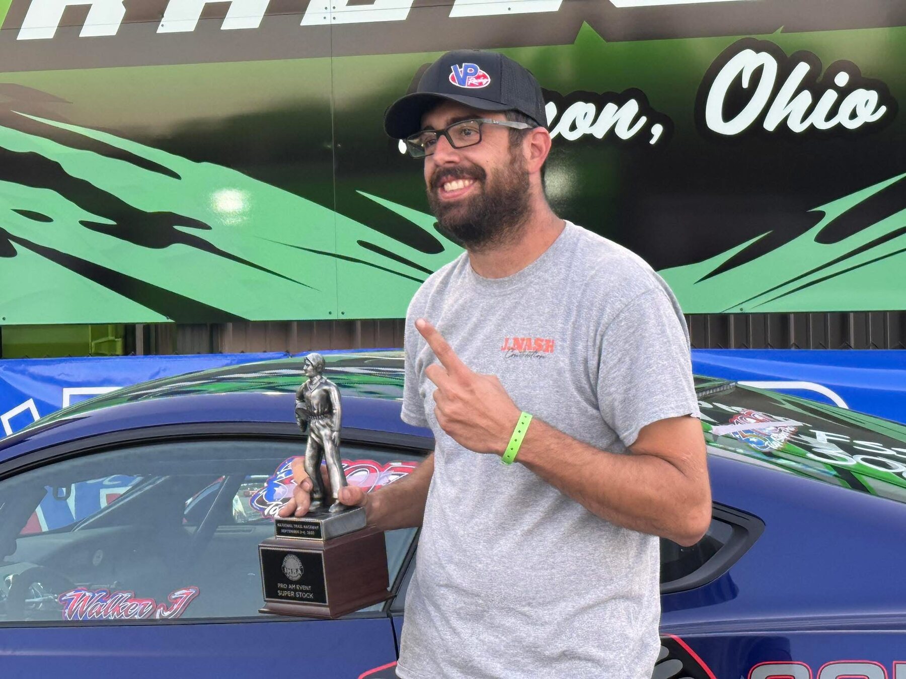 M20 racer holding a trophy beside the race car